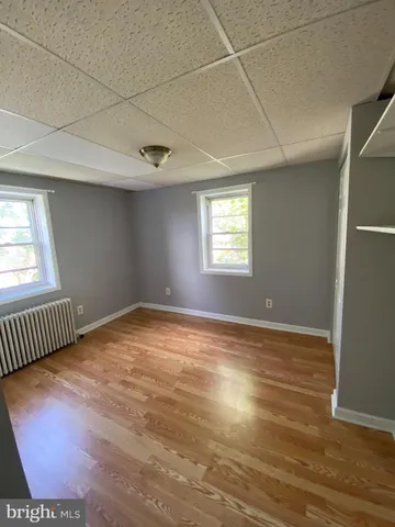 a view of an empty room with wooden floor and fan