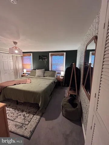 a bedroom with a bed a couch and a flat tv screen on the dresser