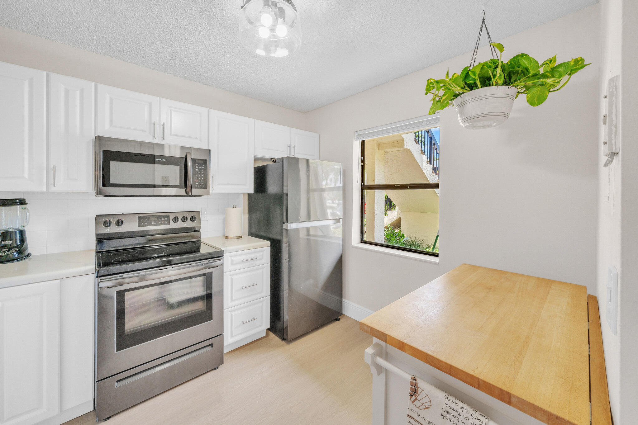 22136 Palms Way, Unit 103 Boca Raton, FL 33433 - Photo 5 of 42 a kitchen with kitchen island granite countertop stainless steel appliances a stove refrigerator sink and microwave