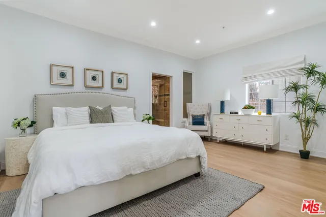 a spacious bedroom with a bed a couch and paintings on the wall