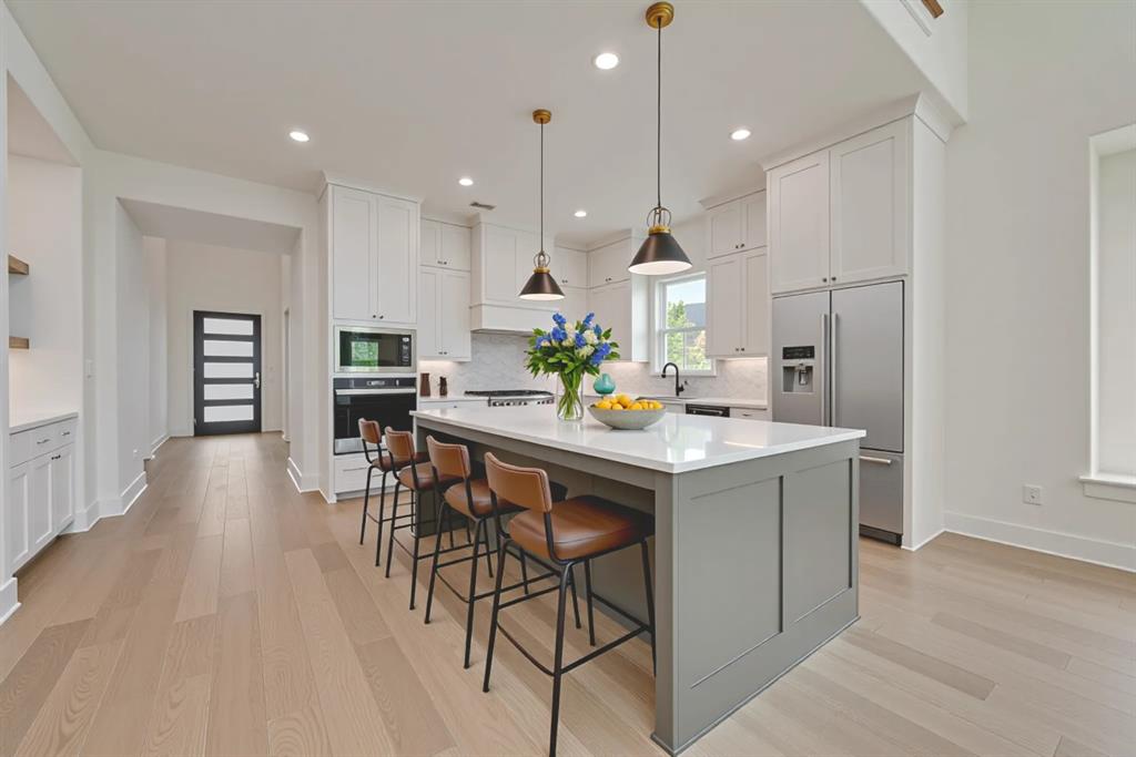16396 Parish Lane Frisco, TX 75033 - Photo 32 of 35 a kitchen with stainless steel appliances kitchen island granite countertop a table chairs and a refrigerator