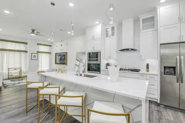 a kitchen with stainless steel appliances granite countertop a stove top oven a sink dishwasher a dining table and chairs with wooden floor