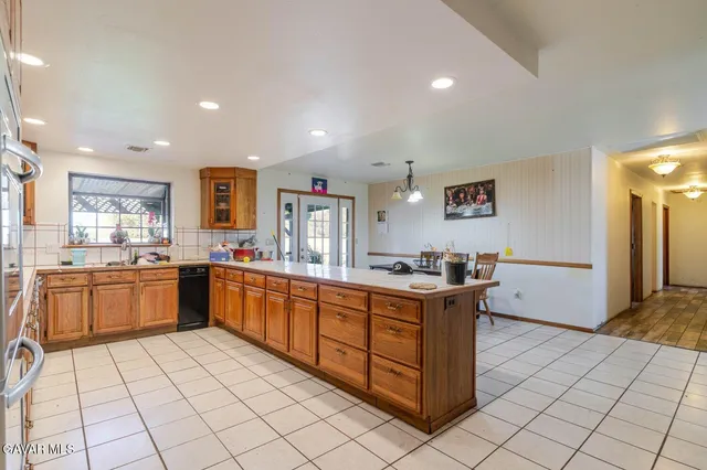 a large kitchen with stainless steel appliances a large counter top a stove and a chandelier