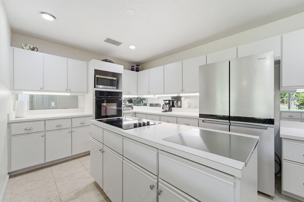 5562 Reynolds Road Lake Worth, FL 33449 - Photo 16 of 39 a kitchen with kitchen island white cabinets and refrigerator