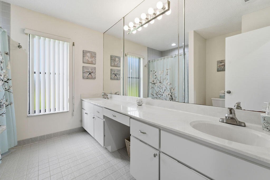 5562 Reynolds Road Lake Worth, FL 33449 - Photo 23 of 39 a bathroom with a granite countertop sink a large mirror a bathtub and shower