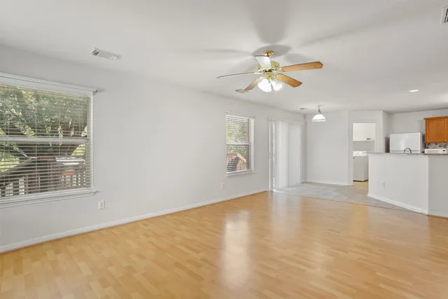 a view of an empty room with window and wooden floor