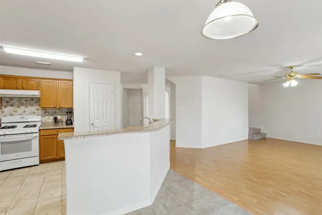 a view of a kitchen with a sink and dishwasher a stove top oven with wooden floor