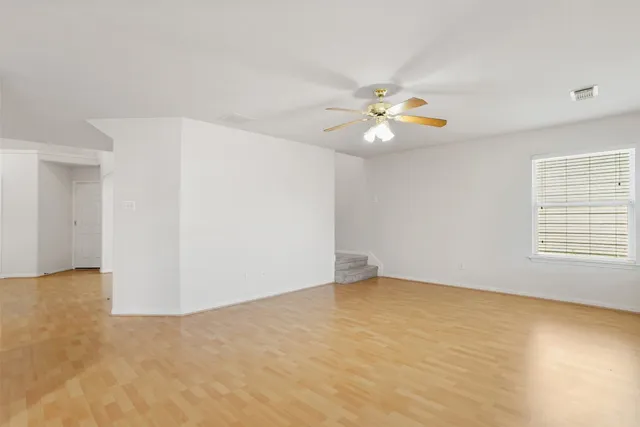 an empty room with a window and a ceiling fan