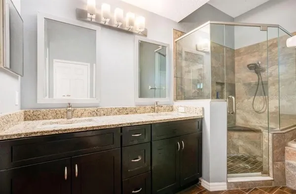 a bathroom with a granite countertop sink vanity mirror and shower