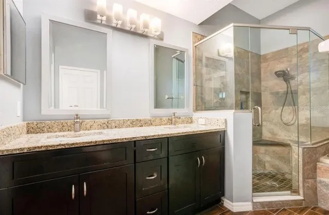 a bathroom with a granite countertop sink vanity mirror and shower