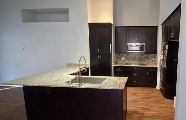 a kitchen with granite countertop a sink and refrigerator
