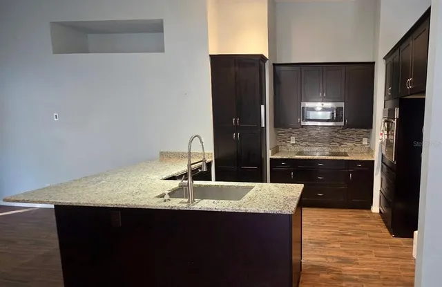 a kitchen with granite countertop a sink and refrigerator