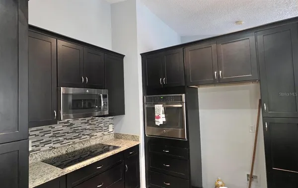 a kitchen with granite countertop a refrigerator and a stove top oven