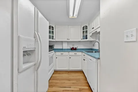 a kitchen with granite countertop white cabinets and white appliances