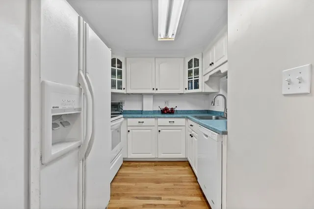 a kitchen with granite countertop white cabinets and white appliances
