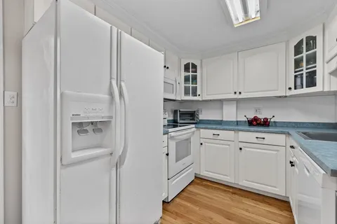 a kitchen with stainless steel appliances granite countertop a refrigerator and white cabinets