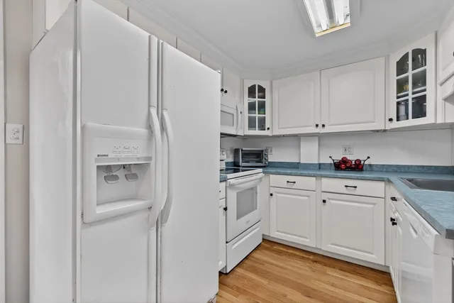 a kitchen with stainless steel appliances granite countertop a refrigerator and white cabinets