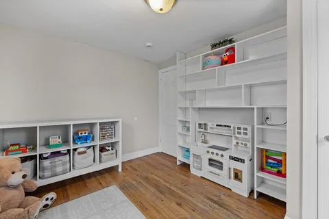 a living room with furniture and a bookshelf with wooden floor