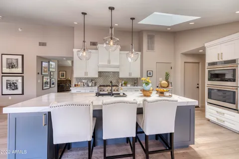 a kitchen with stainless steel appliances a stove a sink a white cabinets and chairs
