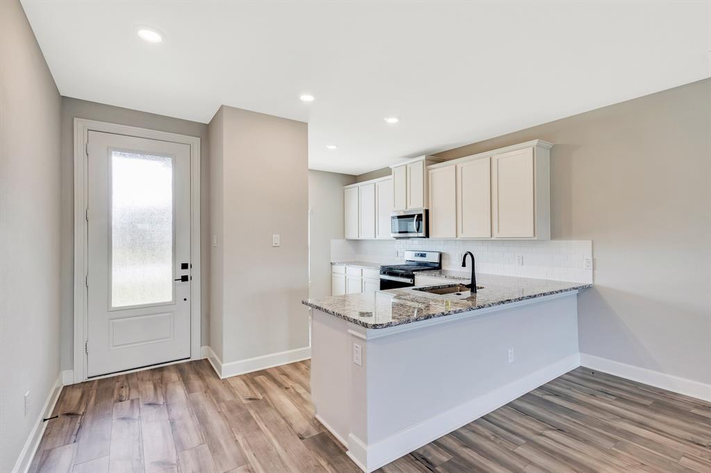 1816 Jeanine Drive Anna, TX 75409 - Photo 4 of 23 a kitchen with kitchen island granite countertop a sink cabinets and wooden floor
