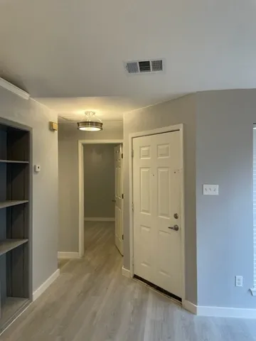 a view of a hallway with wooden floor and a bathroom