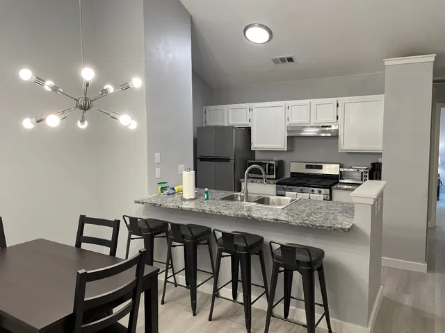 a dining room with stainless steel appliances kitchen island a table chairs and a refrigerator