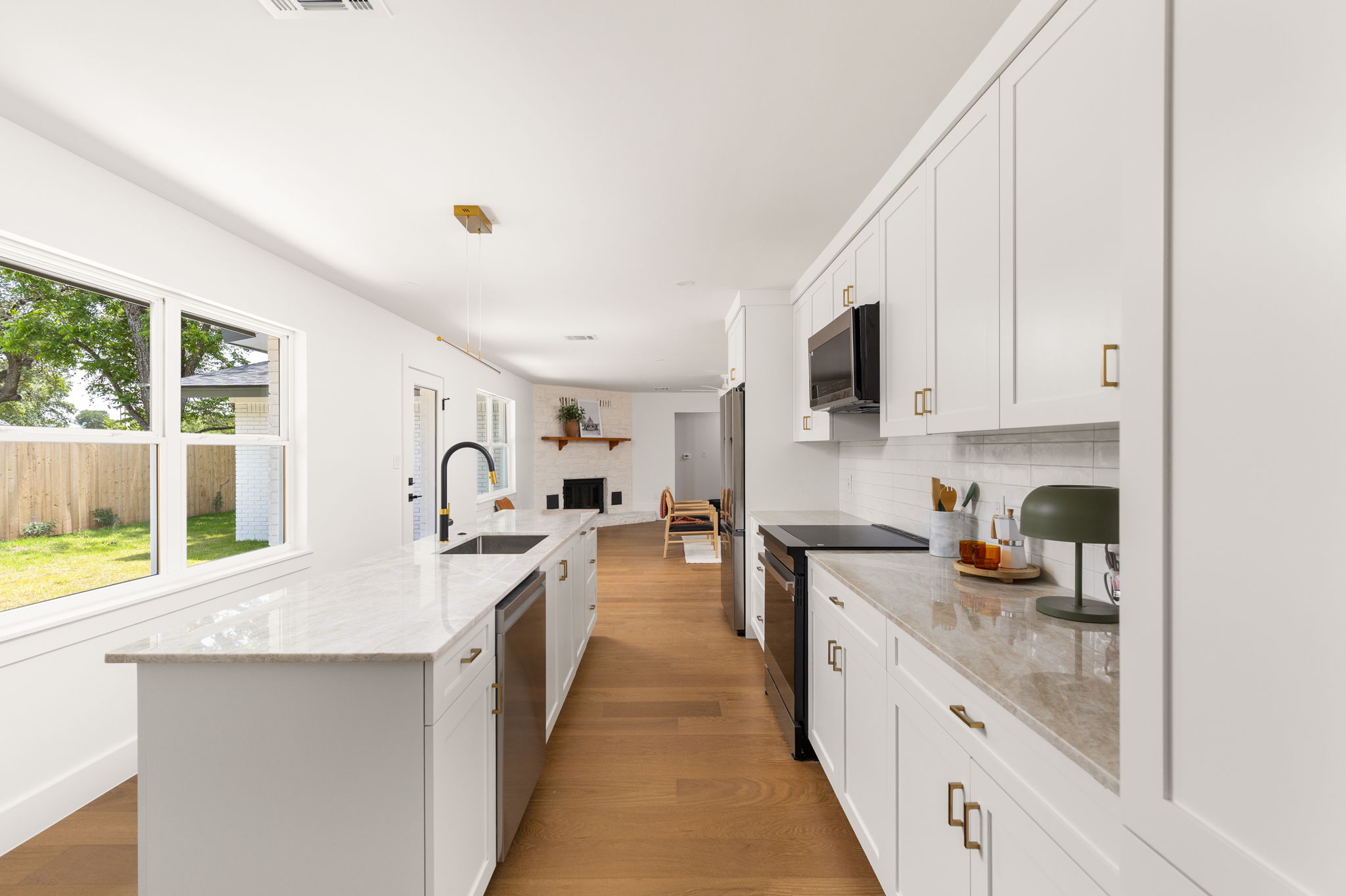 4501 Pack Saddle Pass Austin, TX 78745 - Photo 14 of 37 Modern kitchen featuring white cabinetry, light-toned countertops, stainless steel appliances, and wood-finish flooring