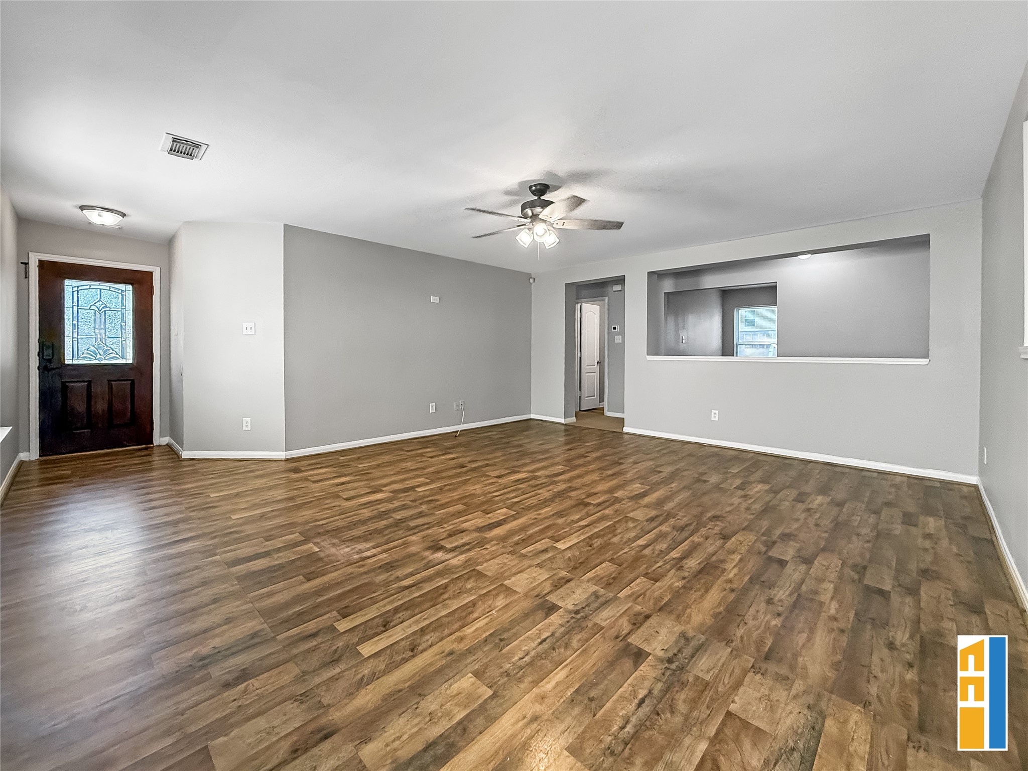 29566 North Legends Bend Drive Spring, TX 77386 - Photo 8 of 21 This inviting living room features elegant wood flooring, a stylish ceiling fan, and abundant natural light from large windows, offering a warm and welcoming space for relaxation and entertainment.