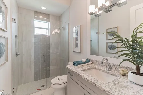 a bathroom with a granite countertop sink a toilet and shower