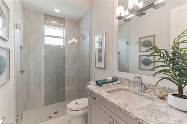a bathroom with a granite countertop sink a toilet and shower