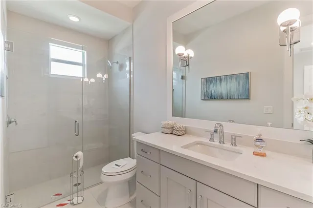 a bathroom with a toilet a sink a mirror a shower and vanity