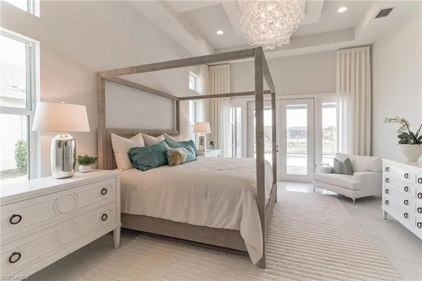 a spacious bedroom with a large bed and a chandelier
