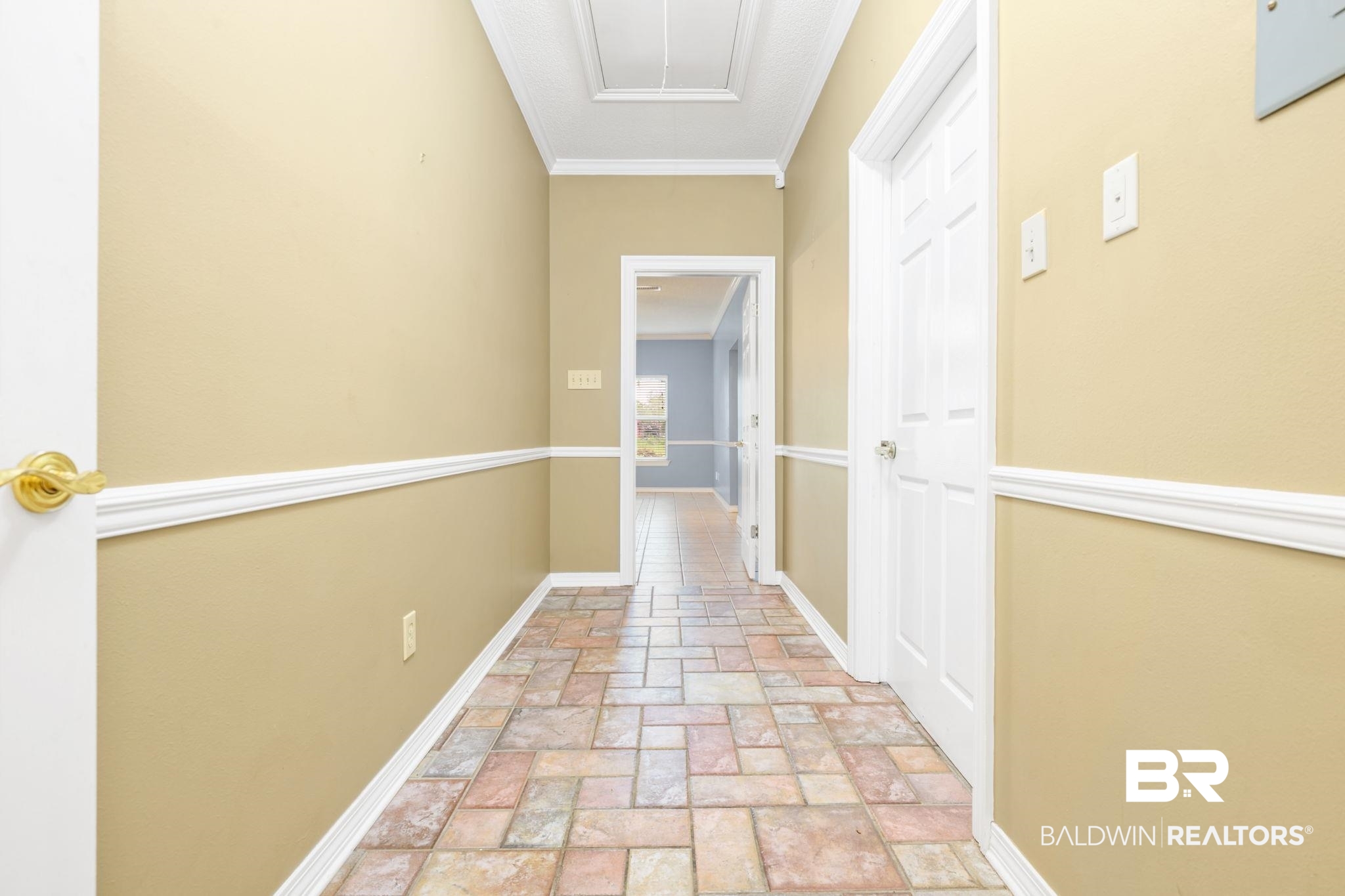 7540 2 Mile Road Irvington, AL 36544 - Photo 26 of 82 Hallway featuring multi-toned tile flooring, neutral wall paint, white baseboards, and white crown molding