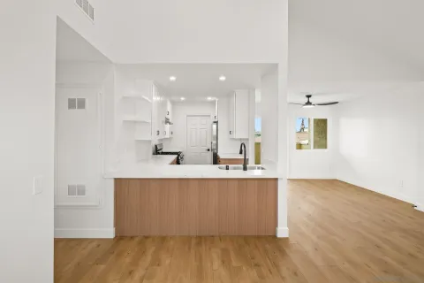 a large white kitchen with wooden floor and a window