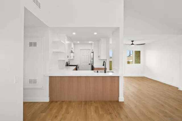 a large white kitchen with wooden floor and a window