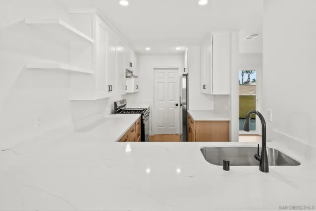 a large white kitchen with sink and a large mirror