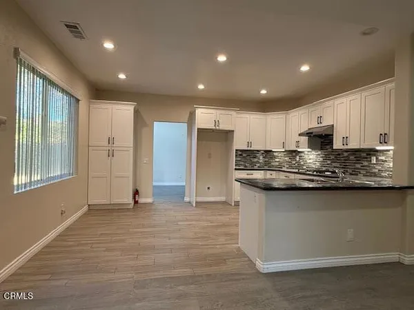 a view of kitchen with stainless steel appliances granite countertop refrigerator stove microwave and cabinets