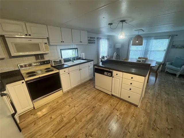 a kitchen with granite countertop a sink a stove and cabinets