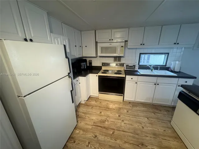 a kitchen with sink a refrigerator and white cabinets