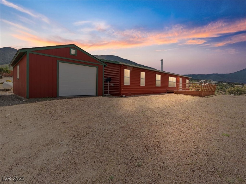 70 West Bonanza Road Las Vegas, NV 89124 - Photo 4 of 71 View of front of property with an outdoor structure, a mountain view, dirt driveway, and faux log siding