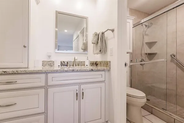 a bathroom with a granite countertop sink toilet and shower