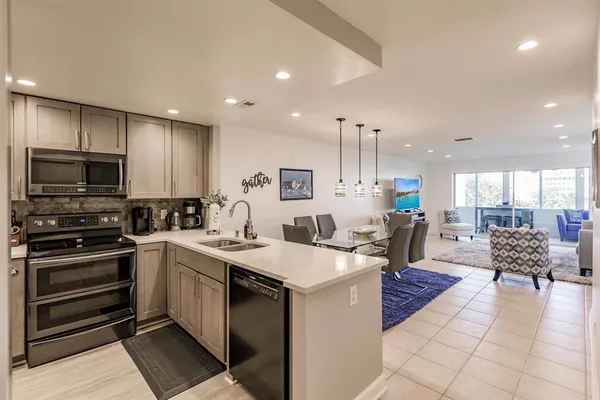 a kitchen with a sink a counter top space appliances and cabinets