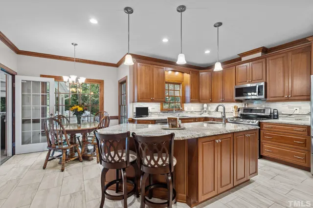 a kitchen with stainless steel appliances granite countertop a stove a sink dishwasher a dining table and chairs with wooden floor