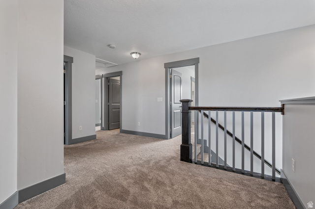 7822 North Copperbend Road Eagle Mountain, UT 84005 - Photo 22 of 46 Carpeted hallway with gray trim and dark wood newel post
