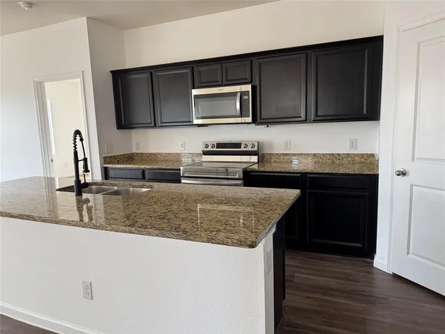 a kitchen with stainless steel appliances granite countertop a sink stove and microwave