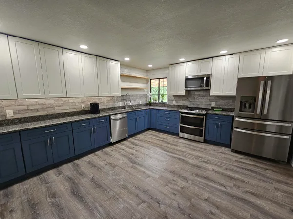 a kitchen with stainless steel appliances granite countertop a stove a sink dishwasher a refrigerator and a oven