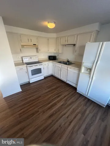 a kitchen with granite countertop white cabinets and white appliances