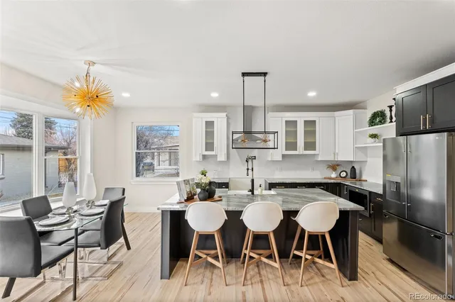 a kitchen with stainless steel appliances a dining table chairs and a refrigerator