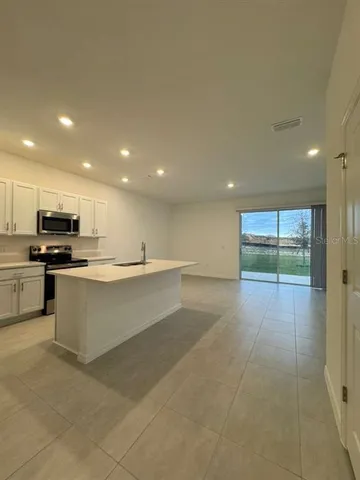 a large white kitchen with stainless steel appliances granite countertop a stove and a sink