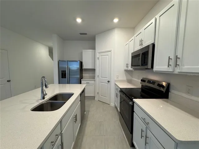 a kitchen with a sink stove top oven and refrigerator